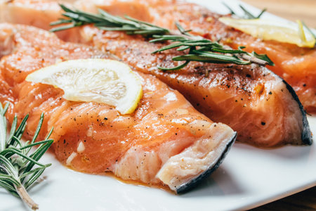 Raw salmon fillet with rosemary pepper thymus and salt on wooden cutting boardの写真素材