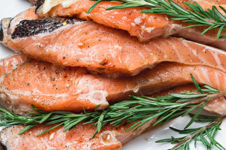 Raw salmon fillet with rosemary pepper thymus and salt on wooden cutting boardの写真素材