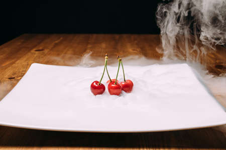 fresh cherry lays on ice on a white plate and soars. close upの写真素材