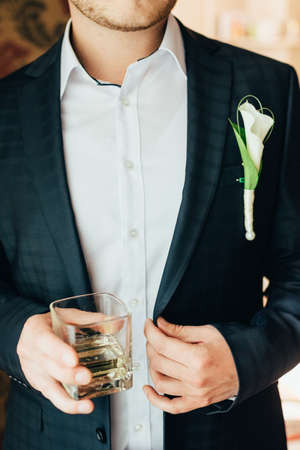 groom holds a glass of whiskey. close upの写真素材