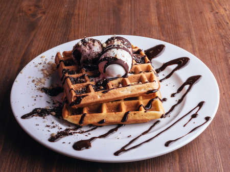 Belgian waffles with ice cream. Chocolate and nuts. wooden table. Rustik .Close upの写真素材