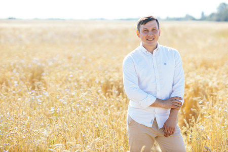 handsome businessman in white shirt standing in field of wheat. outdoor shotの写真素材
