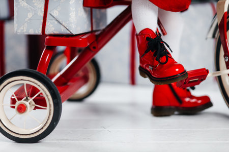 girl in red shoes on a red bicycle with a New Years giftの写真素材