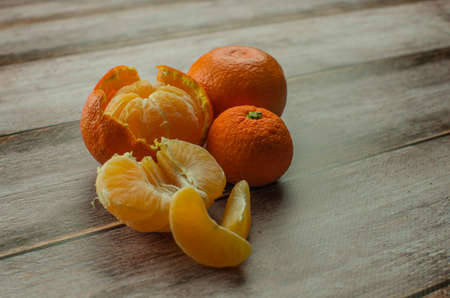 tangerines, peeled tangerine and tangerine slices on a white wooden tableの写真素材