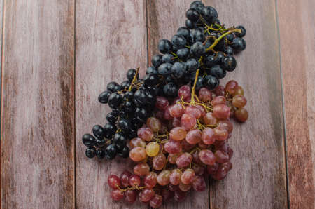 Blue grapes with green leaf healthy eating, isolated on wood background.の写真素材