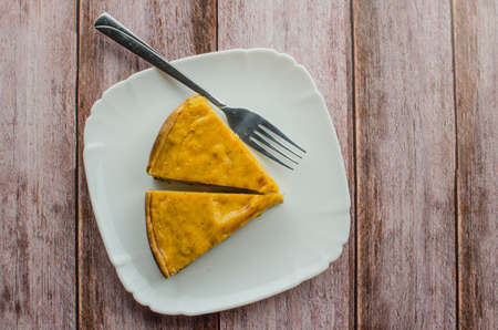 Fresh round bright orange homemade pumpkin pie in baking dish on wood tableの写真素材