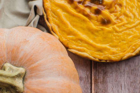 Fresh round bright orange homemade pumpkin pie in baking dish on wood tableの写真素材
