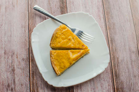 Fresh round bright orange homemade pumpkin pie in baking dish on wood tableの写真素材