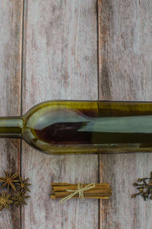 Hot mulled wine drink with lemon, apple, cinnamon, anise and other spices in a glass cup between fir tree branches on wooden cutting board. Copy spaceの写真素材