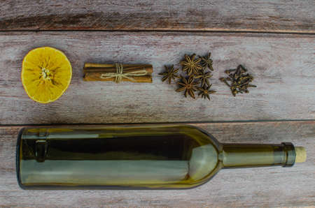 Hot mulled wine drink with lemon, apple, cinnamon, anise and other spices in a glass cup between fir tree branches on wooden cutting board. Copy spaceの写真素材