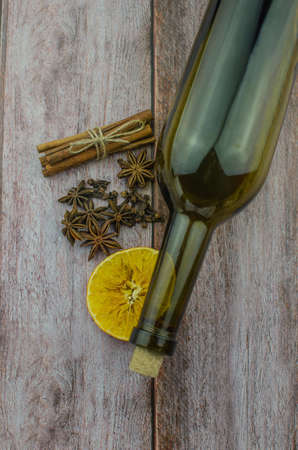 Hot mulled wine drink with lemon, apple, cinnamon, anise and other spices in a glass cup between fir tree branches on wooden cutting board. Copy spaceの写真素材