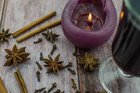 Hot mulled wine drink with lemon, apple, cinnamon, anise and other spices in a glass cup between fir tree branches on wooden cutting board. Copy spaceの写真素材