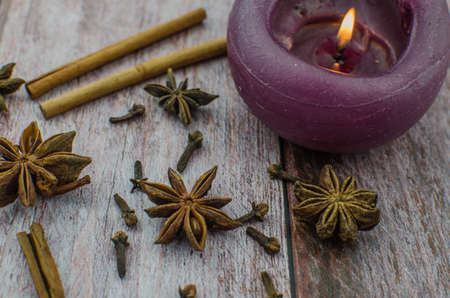 Hot mulled wine drink with lemon, apple, cinnamon, anise and other spices in a glass cup between fir tree branches on wooden cutting board. Copy spaceの写真素材