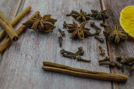 Hot mulled wine drink with lemon, apple, cinnamon, anise and other spices in a glass cup between fir tree branches on wooden cutting board. Copy spaceの写真素材