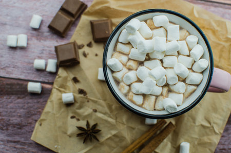 Cocoa drink with spices, zephyr and macaroons on wooden background