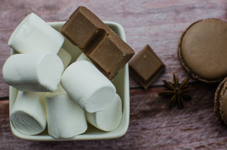 Cocoa drink with spices, zephyr and macaroons on wooden background