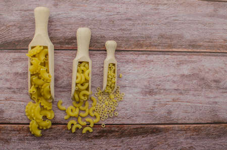 Dried pasta food selection in wooden spoons over old oak background.の写真素材