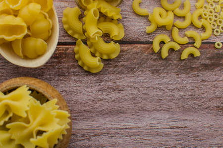 Dried pasta food selection in wooden spoons over old oak background.の写真素材