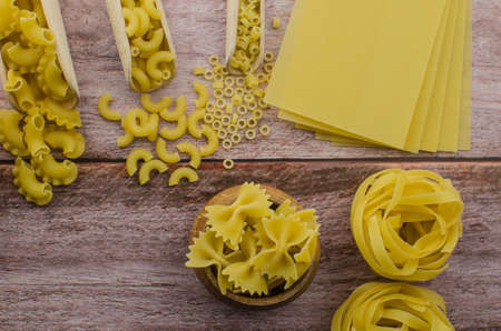 Dried pasta food selection in wooden spoons over old oak background.の写真素材