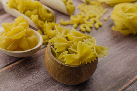 Dried pasta food selection in wooden spoons over old oak background.の写真素材