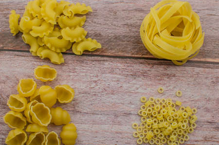 Choosing a meal of dried pasta on a wooden background.の写真素材