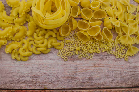 Choosing a meal of dried pasta on a wooden background.の写真素材