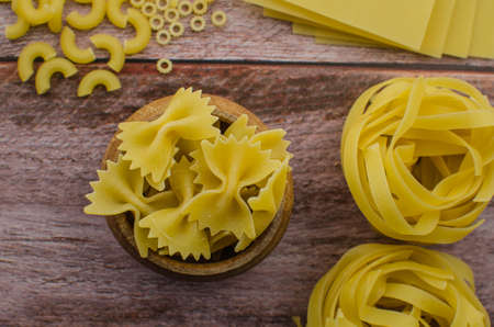Dried pasta food selection in wooden spoons over old oak background.の写真素材