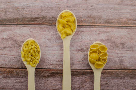 Dried pasta food selection in wooden spoons over old oak background. Copy space for textの写真素材