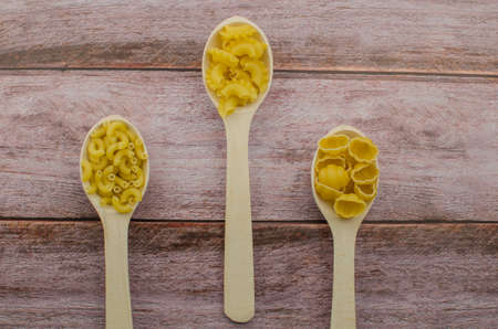 Dried pasta food selection in wooden spoons over old oak background. Copy space for textの写真素材