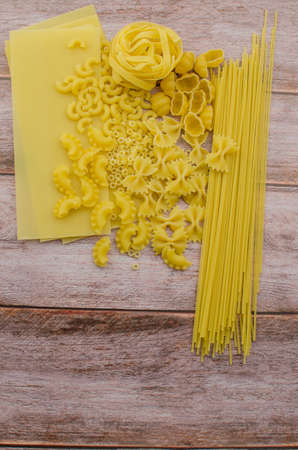 Choosing a meal of dried pasta on a wooden background. Copy space for textの写真素材