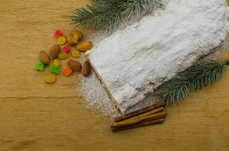 Christmas stollen on darkfestive background with fir twigs, lights and and berries. Close-up on this traditional German dessert for Christmas celebration.の写真素材