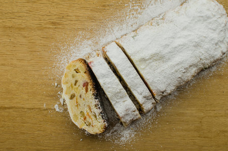 Christmas stollen on darkfestive background with fir twigs, lights and and berries. Close-up on this...