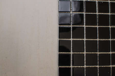 Home repair: installing the mosaic tile on the wall. A worker covers the wall with adhesive using a notched trowel.の写真素材