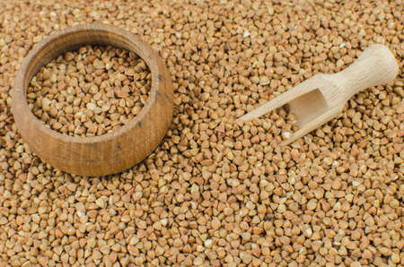 raw buckwheat groats in a clay plate on a wooden background. space for textの写真素材