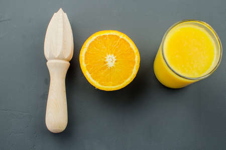 Orange juice and orang with a wooden orange juicer on a black backgroundの写真素材