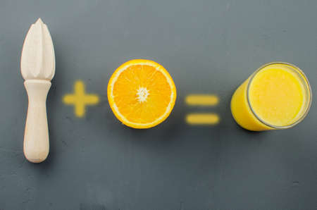 Orange juice and orang with a wooden orange juicer on a black backgroundの写真素材