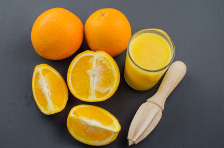 Orange juice and orang with a wooden orange juicer on a black backgroundの写真素材