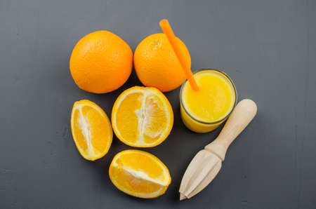 Orange juice and orang with a wooden orange juicer on a black backgroundの写真素材