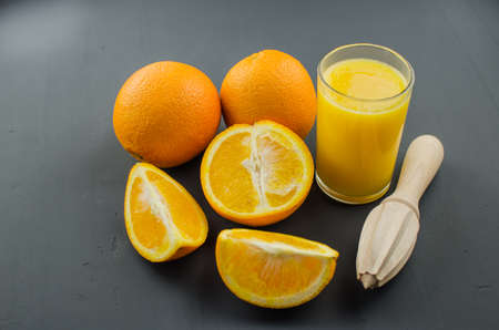 Orange juice and orang with a wooden orange juicer on a black backgroundの写真素材
