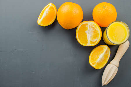 Orange juice and orang with a wooden orange juicer on a black backgroundの写真素材