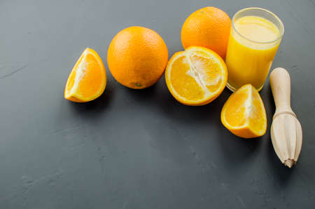 Orange juice and orang with a wooden orange juicer on a black backgroundの写真素材
