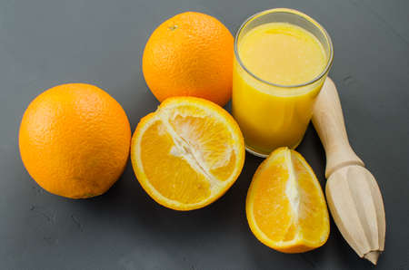 Orange juice and orang with a wooden orange juicer on a black backgroundの写真素材