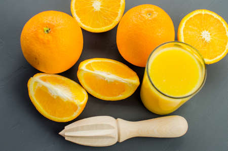 Orange juice and orang with a wooden orange juicer on a black backgroundの写真素材