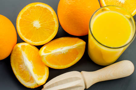 Orange juice and orang with a wooden orange juicer on a black backgroundの写真素材