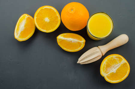 Orange juice and orang with a wooden orange juicer on a black backgroundの写真素材