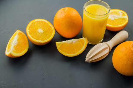 Orange juice and orang with a wooden orange juicer on a black backgroundの写真素材