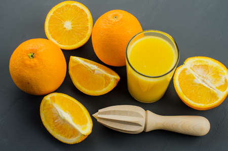 Orange juice and orang with a wooden orange juicer on a black backgroundの写真素材