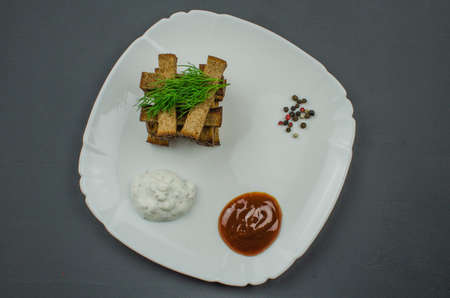 Toasts are fried on a frying pan with spices. Served on a white plate with garlic sauceの写真素材