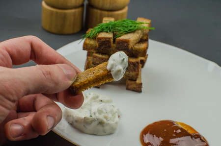 Toasts are fried on a frying pan with spices. Served on a white plate with garlic sauceの写真素材