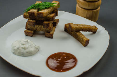 Toasts are fried on a frying pan with spices. Served on a white plate with garlic sauceの写真素材